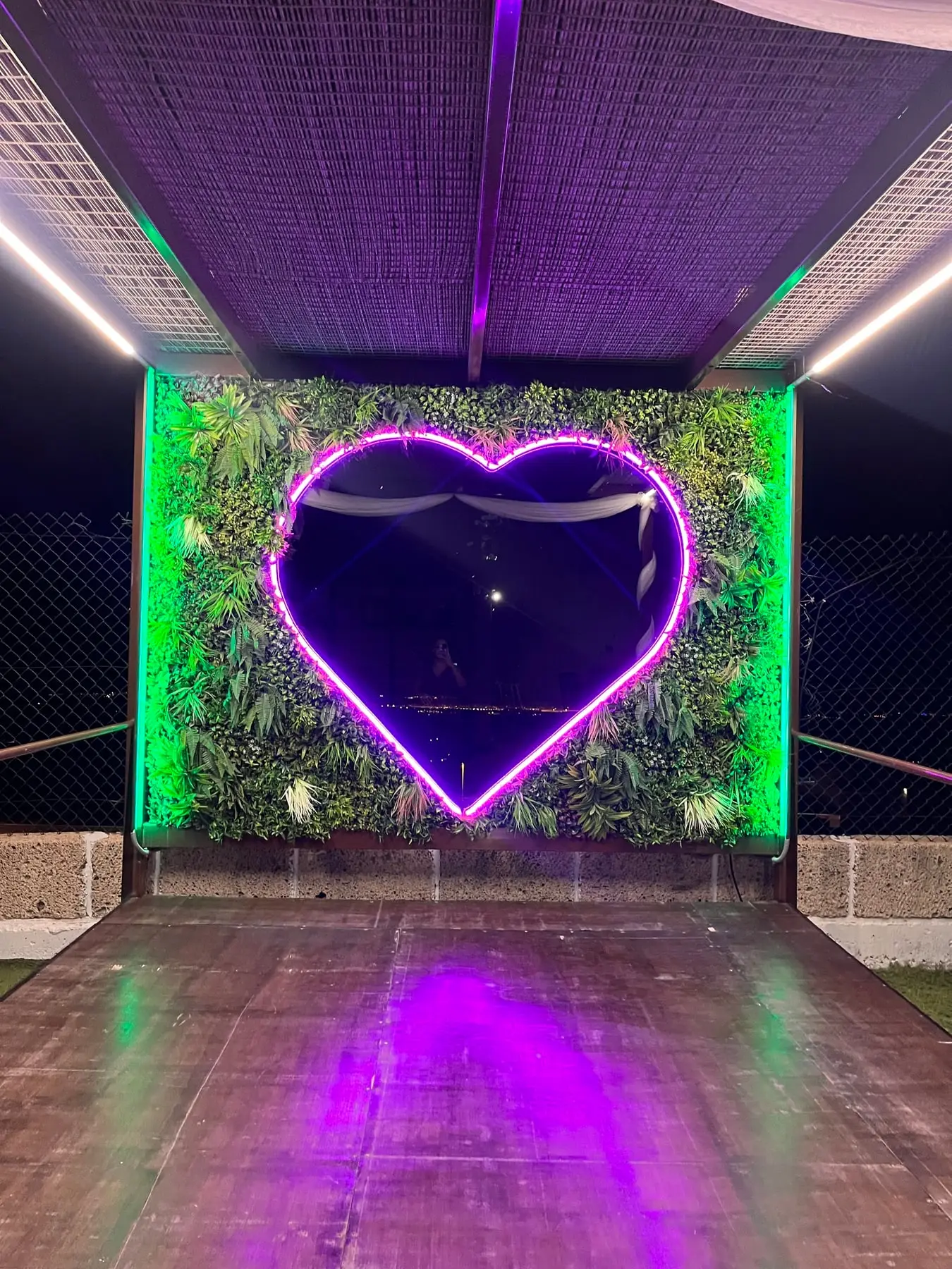 De noche, la tarima del corazón se enciende en morado y verde