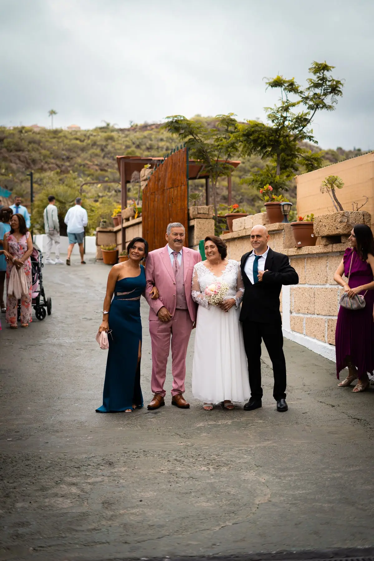 Los novios llegan a pie con sus padrinos, entre invitados y las montañas detrás